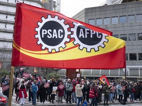 A flag flies as Public Service Alliance of Canada members walk the picket line outside government buildings, Friday, April 21, 2023 in Gatineau, Quebec.