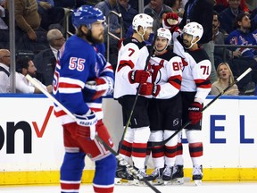 Jack Hughes of the New Jersey Devils (centre) celebrates his goal against Igor Shesterkin of the New York Rangers at 2:50 of the first period and is joined by Dougie Hamilton (left) and Jonas Siegenthaler (right) in Game 4  of the First Round of the 2023 Stanley Cup Playoffs at Madison Square Garden on April 24, 2023 in New York, New York.