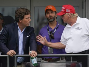 Former U.S. president Donald Trump, right, talks with Donald Trump Jr., centre, and Tucker Carlson at the 16th tee during the final round of the Bedminster Invitational LIV Golf tournament in Bedminster, N.J., July 31, 2022.