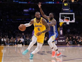 Los Angeles Lakers forward LeBron James dribbles the ball against Golden State Warriors forward Andrew Wiggins.