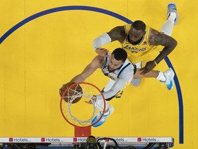 Golden State Warriors guard Stephen Curry shoots the ball against Los Angeles Lakers forward LeBron James.
