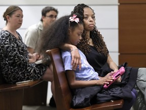 Philana Holmes and her daughter Olivia Caraballo, 7 listen to the final witness in their case at the Broward County Courthouse in Fort Lauderdale, Fla., on Wednesday May 10, 2023.
