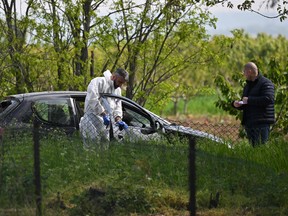 A forensic investigator works at one of the crime scenes, outside of the village of Dubona near the town of Mladenovac, about 60 kilometres (37 miles) south of Serbia's capital Belgrade, on May 5, 2023, in the aftermath of a drive-by shooting.