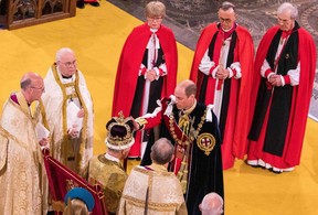 Britain’s Prince William, Prince of Wales touches St Edward’s Crown on the head of his father, Britain’s King Charles III, during the King’s Coronation Ceremony inside Westminster Abbey in central London on May 6, 2023.
