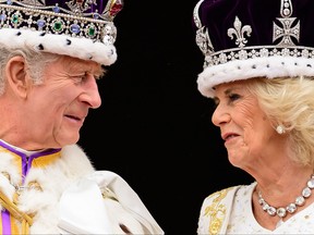 Britain's King Charles III (L) looks at Queen Camilla as they stand on the Buckingham Palace balcony, in London, following their coronations, on May 6, 2023.