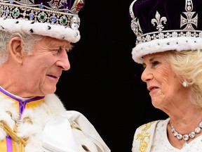 Britain's King Charles III (L) looks at Queen Camilla as they stand on the Buckingham Palace balcony, in London, following their coronations, on May 6, 2023.