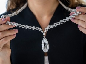 This photograph taken on May 8, 2023, shows an employee of Christie's auction house holding the "Briolette of India" a 90.36 carats colourless (D) diamond, a diamond necklace expected to fetch at least 10 million USD at the World of Heidi Horten sale in Geneva.