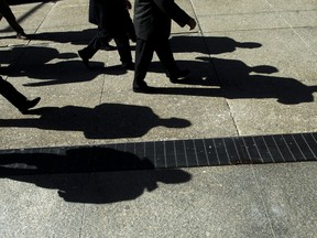 Businessmen cast their shadows as they walk in Toronto's financial district