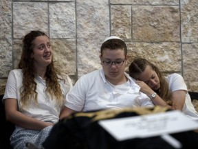 The three remaining children of Lucy Dee comfort each other at their mother's funeral in the West Bank Jewish settlement of Kfar Etzion, Tuesday, April 11, 2023.