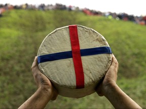 A Double Gloucester cheese is held up at Cooper's Hill, Gloucestershire