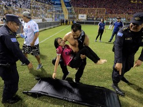 Supporters are helped by others following a stampede during a football match between Alianza and FAS at Cuscatlan stadium in San Salvador, on May 20, 2023.