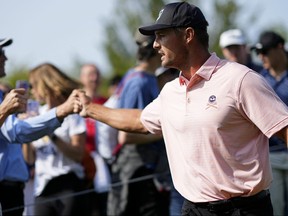 Bryson DeChambeau fist-bumps fans as he walks off the ninth green after completing the first round of the PGA Championship golf tournament at Oak Hill Country Club.