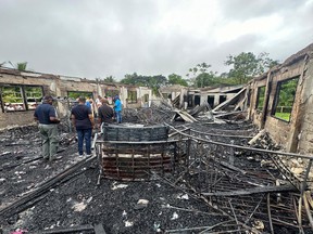People stand inside the remains of a secondary school dormitory after several children  died after a fire gutted the building in Mahdia, Guyana on 22 May, 2023.
