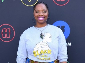 Black woman in colourful skirt and baby blue shirt emblazoned with 'Black Lives Matter'