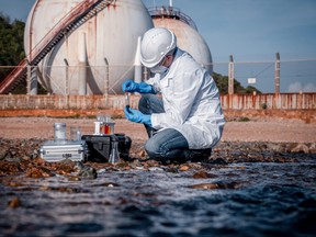 A scientist wearing safety uniform and glove takes a wastewater sample in this photo illustration.