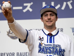 Trevor Bauer with his new uniform and cap of Yokohama DeNA BayStars poses for photographers during a news conference Friday, March 24, 2023, in Yokohama, near Tokyo.