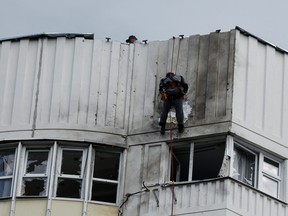 Workers repair damage on the roof of an apartment block following a reported drone attack