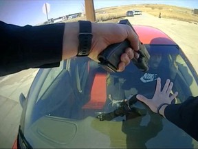 Bodycam footage shows a police officer pointing a gun at a driver after mounting his car during a traffic stop to prevent a getaway, in Carroll, Iowa.