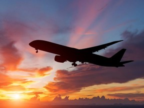 A silhouette of a passenger plane flying in the sunset.