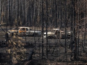 Burnt out trucks from a wildfire sit on a property near Drayton Valley, Alta.,