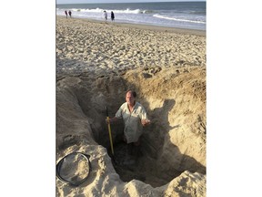 David Elder, ocean rescue supervisor for Kill Devil Hills, N.C, stands in a hole he estimates to be 7 feet deep