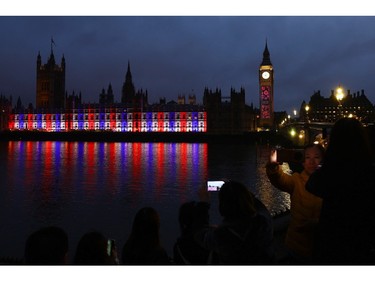 People take pictures of the illuminated Houses of Parliament following the coronation ceremony of King Charles and Queen Camilla in London, May 6, 2023.
