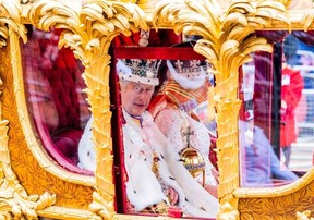 King Charles and Queen Camilla looks on as the Coronation Procession passes on its way to Buckingham Palace in London, May 6, 2023.
