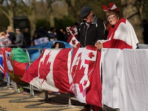 Bernadette Christie, right, and her husband Bruce Christie of Grand Prairie, Alta., hang their Canadian flags along the fence where she and her husband are camped out days before the official coronation of King Charles III near Buckingham Palace along the Mall in London, Wednesday, May 3, 2023.