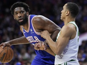 Philadelphia 76ers' Joel Embiid, left, tries to get past Boston Celtics' Malcolm Brogdon during the first half of Game 4 in an NBA basketball Eastern Conference semifinals playoff series, Sunday, May 7, 2023, in Philadelphia.