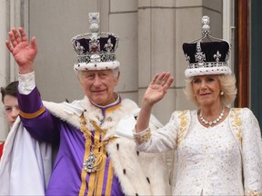 King Charles III wearing the Imperial state Crown, and Queen Camilla wearing a modified version of Queen Mary's Crown wave from the Buckingham Palace balcony after viewing the Royal Air Force fly-past in central London on May 6, 2023, after their coronations.