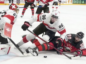Goalie Leonardo Genoni, left, and Janis Moser, centre of Switzerland, fight for a puck with Joe Veleno of Canada during the group B match between Switzerland and Canada at the ice hockey world championship in Riga, Latvia, Saturday, May 20, 2023.