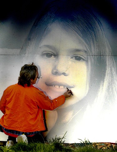Local artist Olaf Schneider uses a projector to help him draw a picture of Holly Jones on a wall.