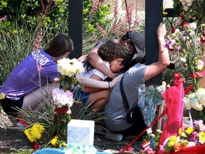 A mother (who didn't want to provide her name) is comforted as she visits a cross that bears the name of one of her children's best friends at the memorial set up near the scene of a mass shooting at the Allen Premium Outlets mall on May 9, 2023 in Allen, Texas.