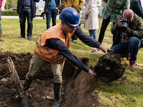 Bystanders look on as an employee of the Historical Circle Kesteren removes earth from a freshly dug trench in Ommeren on May 1, 2023.