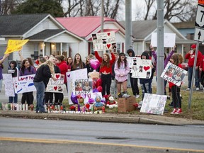 People gather at the intersection of 5th Avenue and 31st Street (U.S. 60) in Huntington, W.Va., on Sunday, Jan. 1, 2023, for a candlelight vigil.