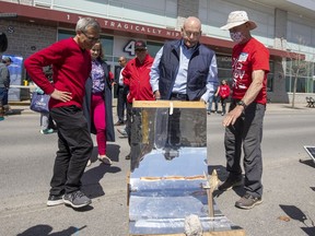 Ted Hsu and Steven Del Duca watch hotdogs being roasted.