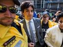 Toronto Police Const. Robert Konashewych -- left and closest to the camera -- is pictured in a May 11, 2016 photo. The photo is unrelated to Konashewych's current trial. The photo shows former CBC radio host Jian Ghomeshi as he makes his way to a Toronto courthouse where he signed a peace bond and apologized to a complainant. The Crown then withdrew a charge of sexual assault against Ghomeshi. 