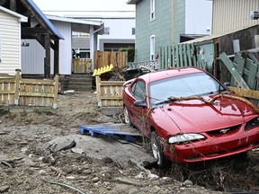 A car lies in the backyard of a house after a major spring flood hit Baie-Saint-Paul, Que., on Wednesday, May 3, 2023.