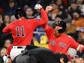Boston Red Sox third baseman Rafael Devers (11) celebrates with designated hitter Justin Turner (2)] after hitting a home run against the Toronto Blue Jays during the eighth inning at Fenway Park.