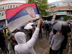 A protester waves a Serbian national flag in front of the Radio Television of Serbia
