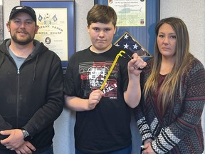 Andrew Burns, left, Owen Burns, centre, and Margaret Burns pose with a slingshot Owen used to thwart an alleged kidnapping attempt of his sister, on Wednesday, May 17, 2023, in Alpena Township, Mich.