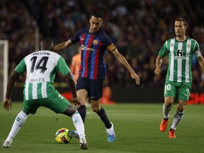Barcelona's Sergio Busquets, center, is challenged by Betis' William Carvalho, left, and Betis' Sergio Canales during a Spanish La Liga soccer match between Barcelona and Real Betis at the Camp Nou stadium in Barcelona, Spain, Saturday, April 29, 2023.