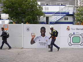 Workers pass a poster of Real Madrid's Vinicius Junior