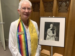 Cathy Sayle, a coordinator at St. Paul’s United Church in Orillia, Ont., poses by a photo of Gordon Lightfoot as a choir boy there. (Jane Stevenson/Toronto Sun)