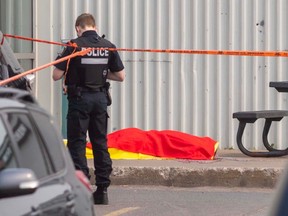 A Montreal police officer stands next to the body of mobster Francesco Del Balso, who was shot and killed outside Monster Gym in Dorval on Monday June 5, 2023.