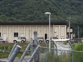 Vehicles and members of Japan's Ground Self-Defense Force (SDF) are pictured outside a building at the Hino basic firing range in the city of Gifu, Gifu prefecture, on June 14, 2023, where a shooting incident occurred at the training range. Two soldiers were killed and a third wounded when a fellow recruit opened fire at the training range in central Japan on June 14, the military said. (Photo by JIJI Press / AFP)