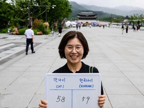 In this picture taken in Seoul on June 21, 2023, Lee Jung-hee, poses with a whiteboard showing her international age, 58, and Korean age, 59.