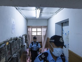 Police officers walk up an apartment where three children were killed in Sham Shui Po in Hong Kong, Monday, June 5, 2023.