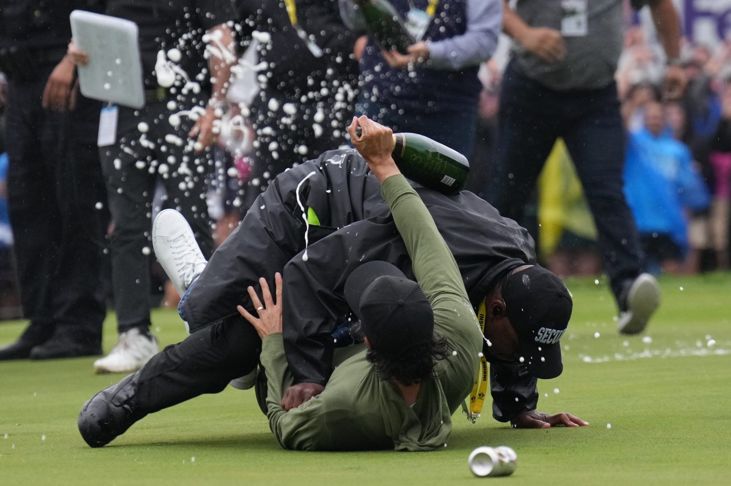 Canadian professional golfer Adam Hadwin, bottom, is stopped by a security guard while he tries to celebrates with Nick Taylor, of Canada, after Taylor won the Canadian Open championship on the fourth playoff hole on Sunday. 
