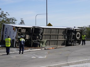 Police inspect a bus on its side.